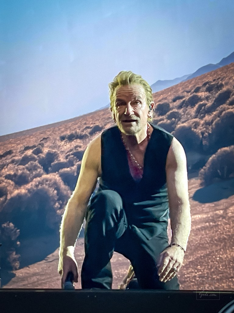 A close up photo of Bono wearing a vest and kneeling on one knee. From the U2:UV Achtung Baby at the Sphere concert in Las Vegas March 1, 2024. 