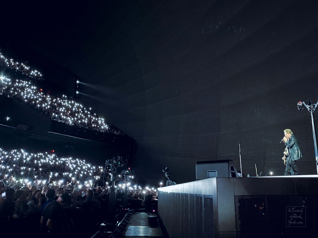 A photo of U2 and the audience at the U2:UV Achtung Baby at the Sphere concert in Las Vegas March 1, 2024. The audience have their phone lights on, creating a sea of stars.