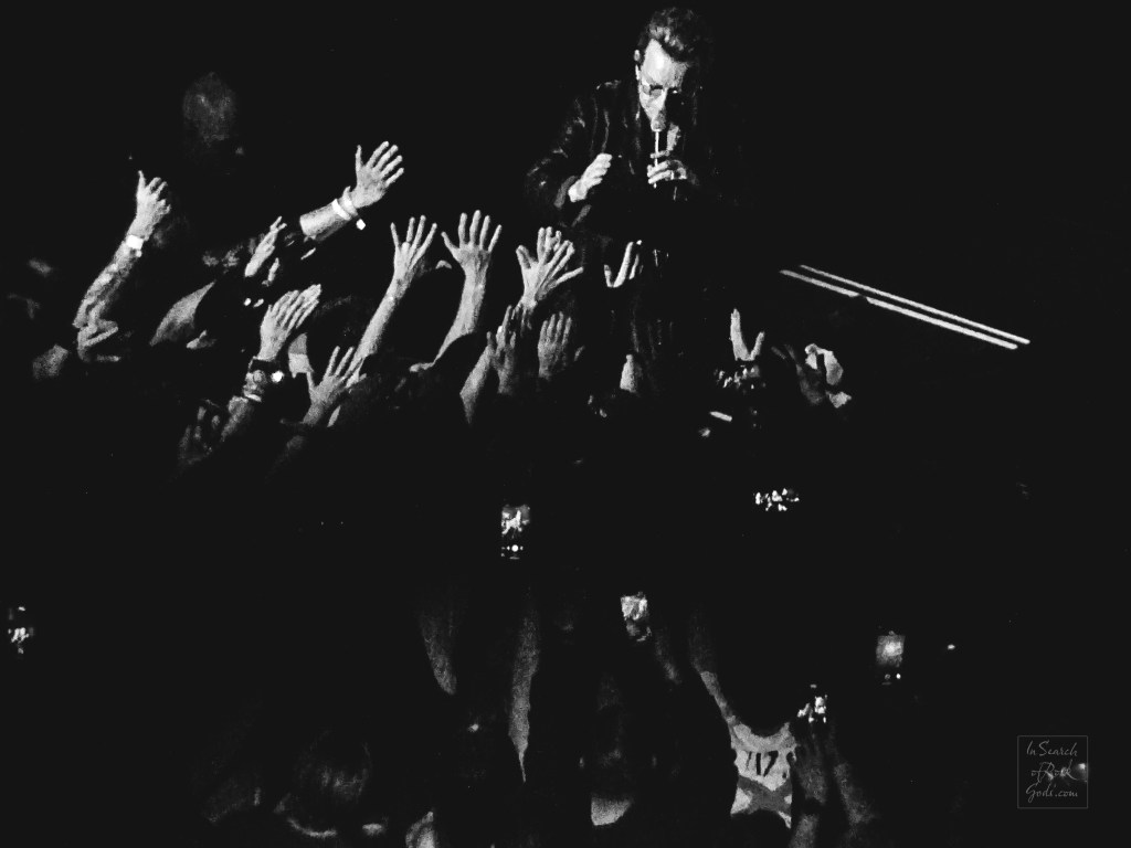 A black and white photo of Bono reaching into the crowd and many hands reaching back at the U2:UV Achtung Baby at the Sphere concert in Las Vegas March 2, 2024. 