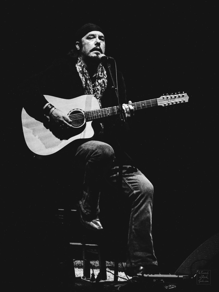 Black and white photo of Jeff Martin sitting with Guitar at the Northern Alberta Jubilee Auditorium